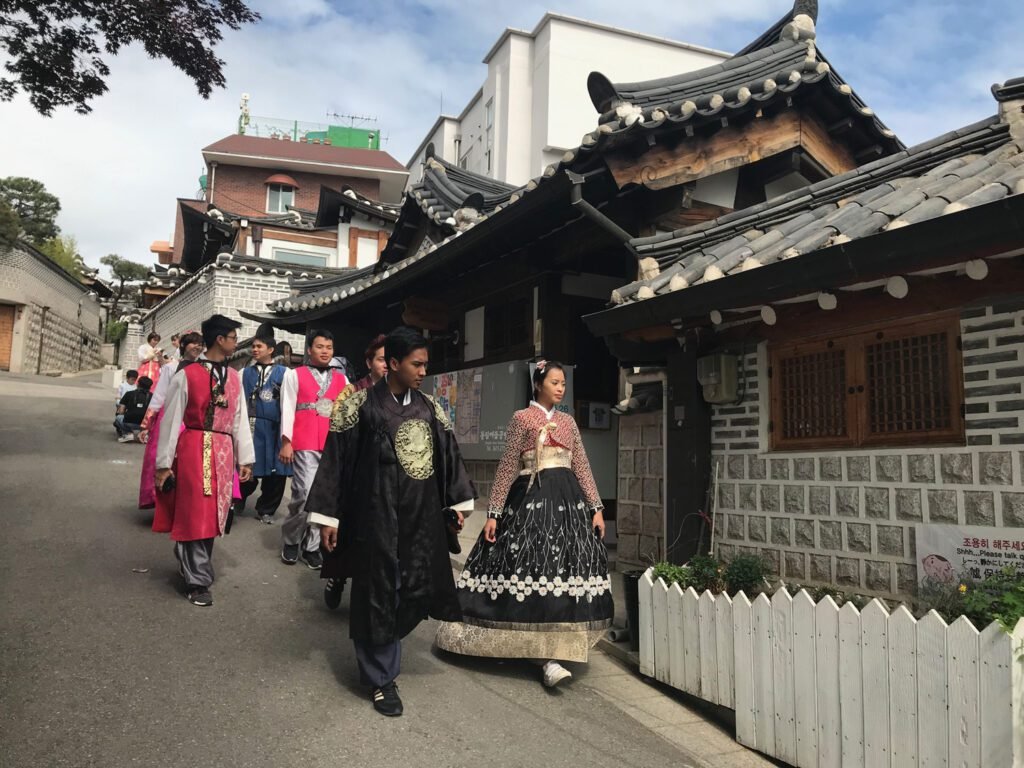People strolling amongst the wooden Hanok houses in traditional costumes at Bukchon Hanok Village.